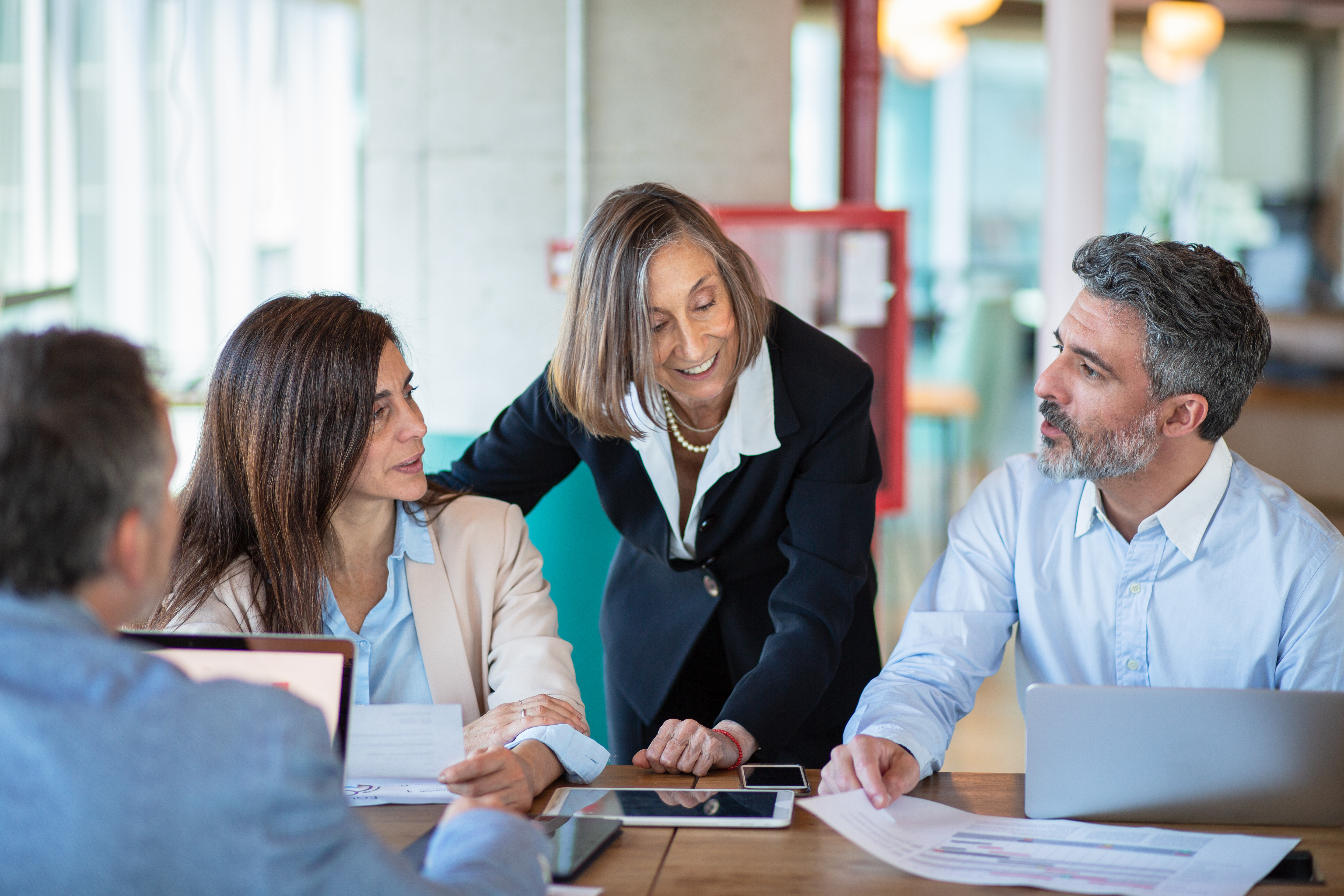 Four colleagues discussing business strategy in modern open-plan office